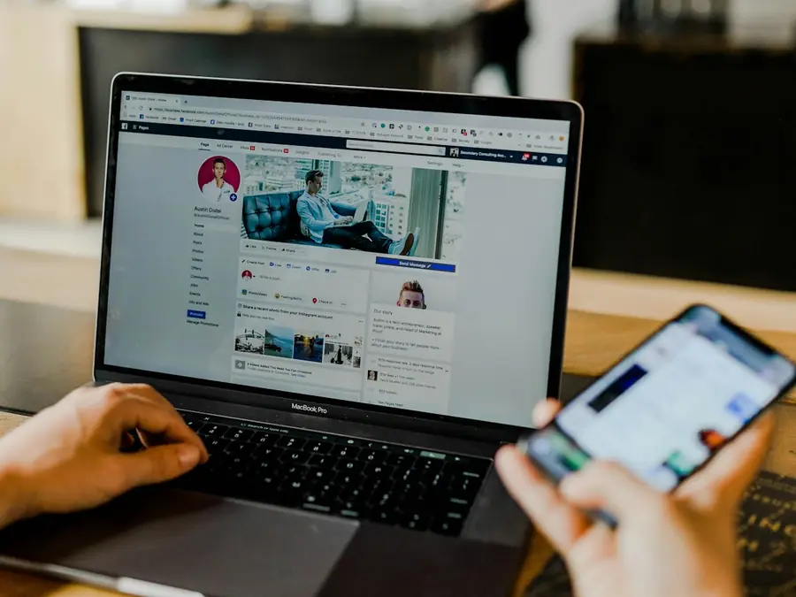 Person managing a social media page on a laptop and a smartphone