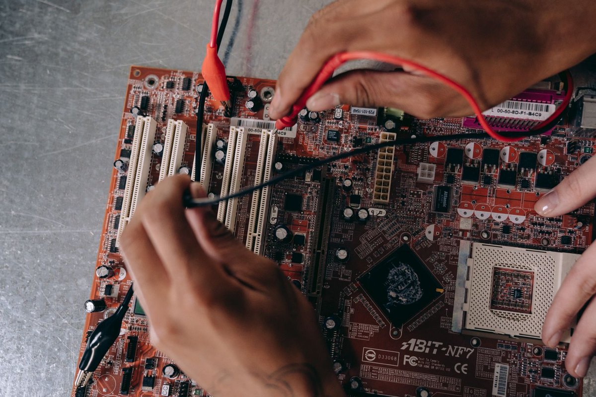 Hands working on a motherboard with repair tools