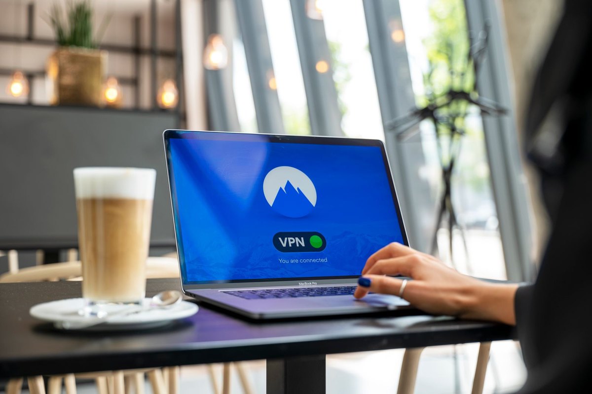 Person using a laptop showing a VPN connection, in a cafe