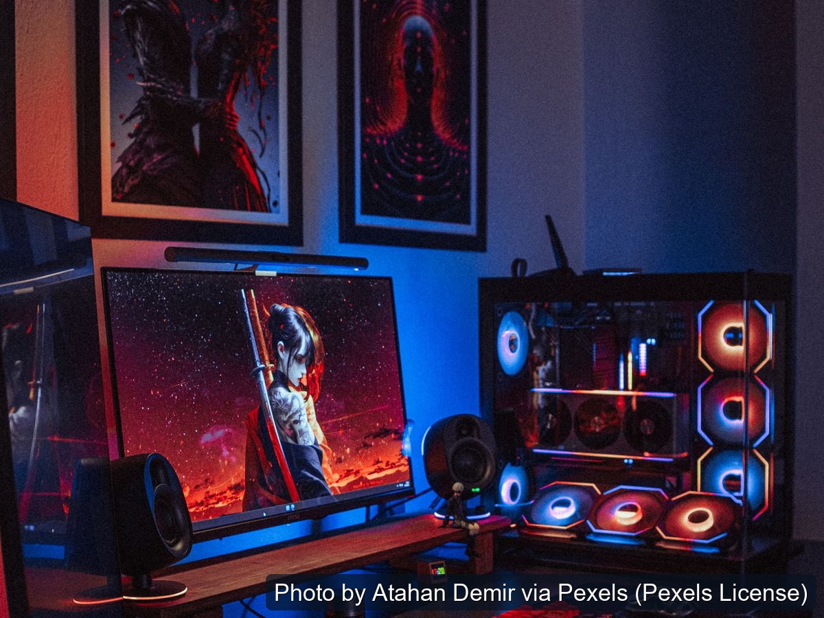 Custom gaming computer tower with lit fans beside monitors