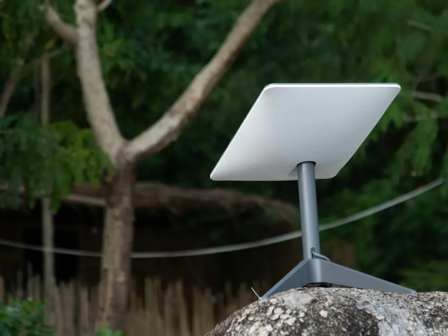 Flat satellite internet dish on a stand outdoors among trees