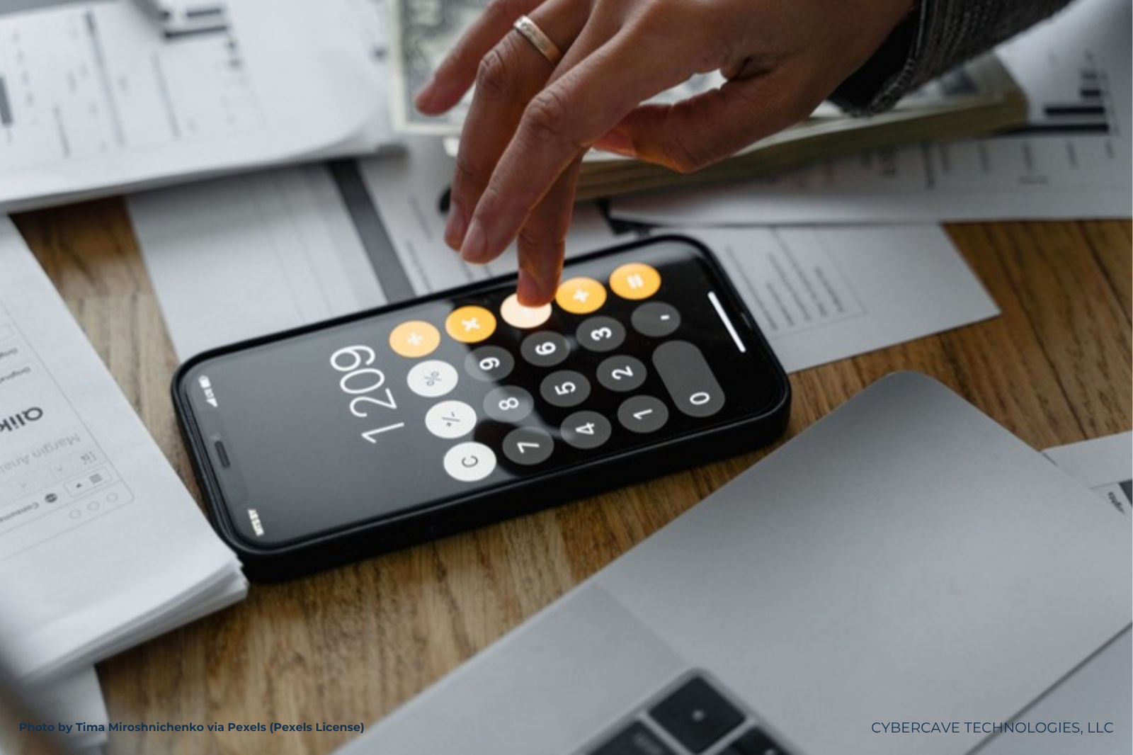 A hand checking figures on a smartphone calculator beside paper documents