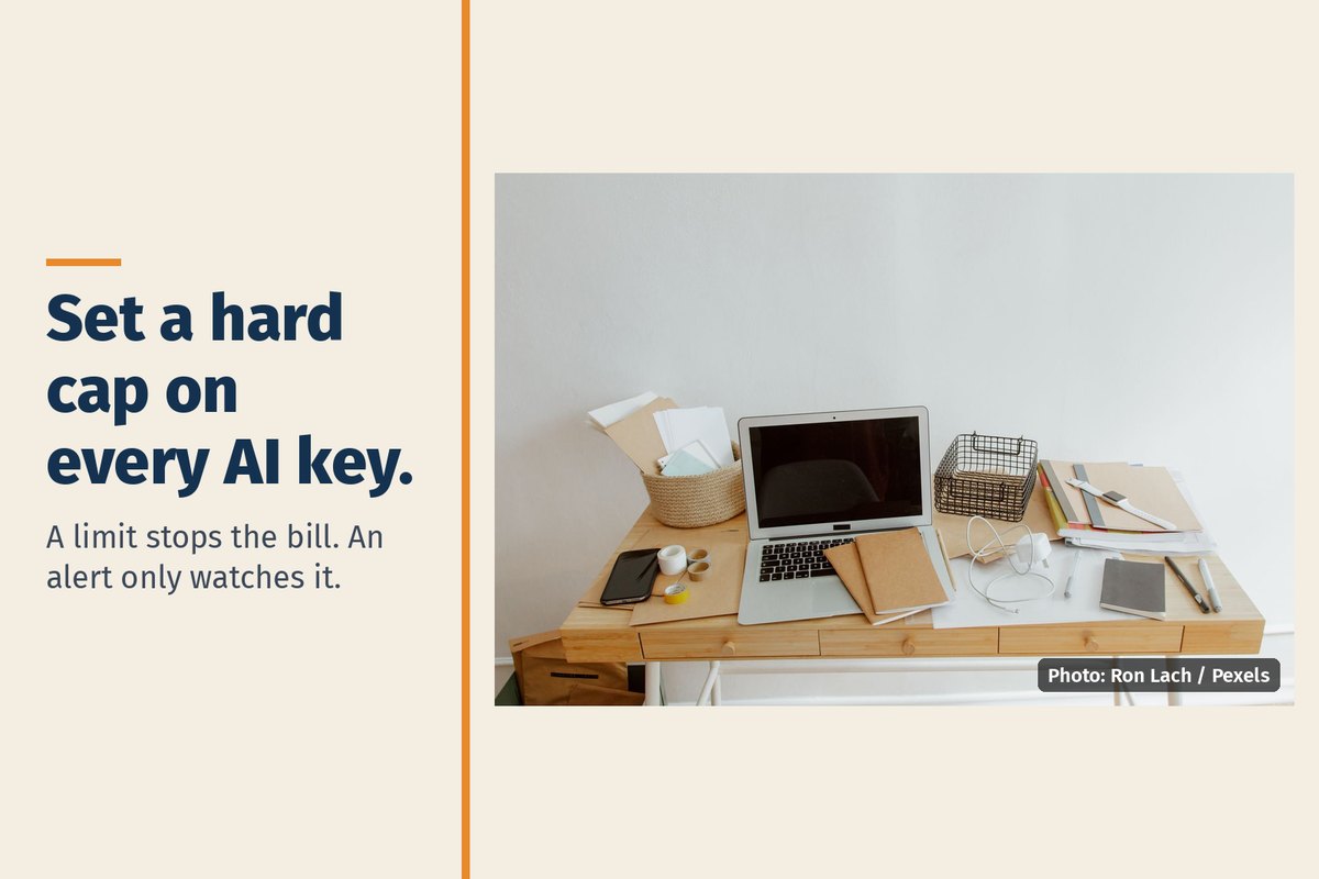 A desk with a laptop, notebooks and a phone, with the words "Set a hard cap on every AI key. A limit stops the bill. An alert only watches it."