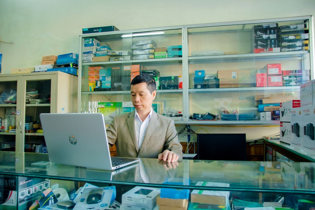 Man using a laptop in an electronics shop, devices on display